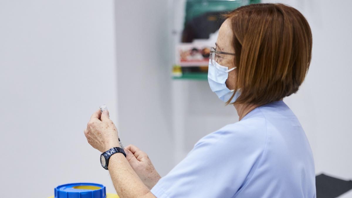 Una trabajadora sanitaria sostiene una jeringuilla,