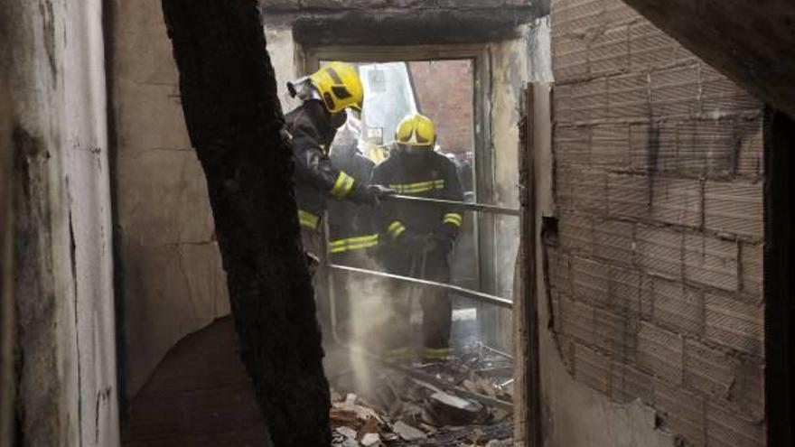 Varios bomberos en el interior de la vivienda que se incendió y se derrumbó.