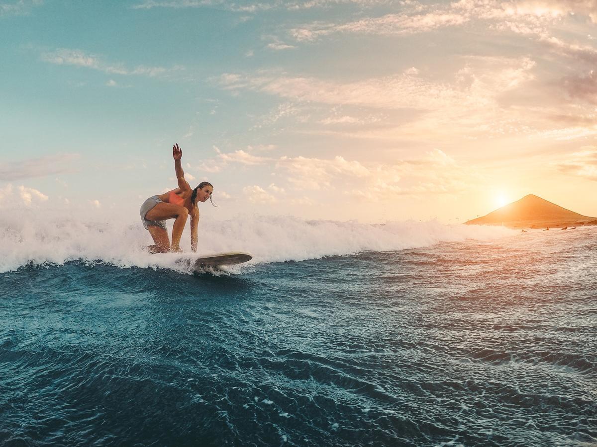 De viaje se pueden vivir experiencias únicas, como surfear al atardecer.
