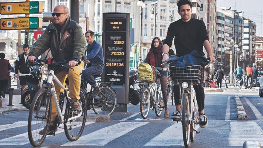 Ciclistas circulan frente al contador de bicicletas instalado por el Ayuntamiento de València en la calle Colón.