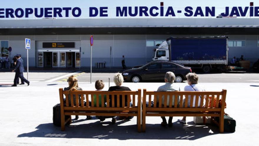 Un grupo de viajeros descansa frente a las puertas del aeropuerto de San Javier.