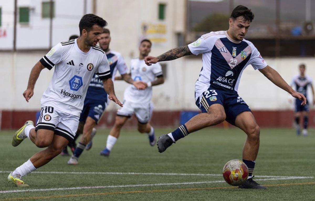 Dani, del San Fernando, controla el balón presionado por Kevin, del Arucas, ayer en El Tablero.