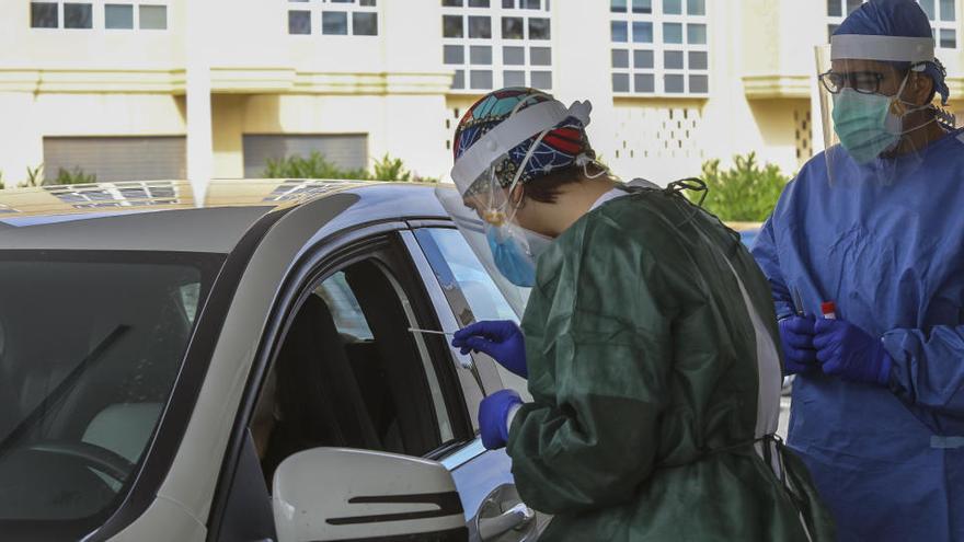 Dos enfermeros de Elche toman muestras a un paciente en su vehículo para realizar una prueba PCR, en imagen de archivo. NTONIO AMORÓS