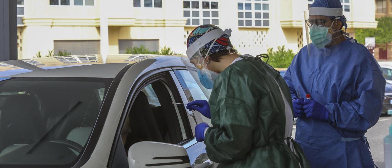 Dos enfermeros de Elche toman muestras a un paciente en su vehículo para realizar una prueba PCR, en imagen de archivo. NTONIO AMORÓS