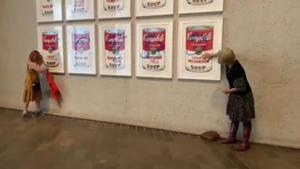 Dos activistas se pegan a las latas de sopa Campbell de Warhol en Australia.