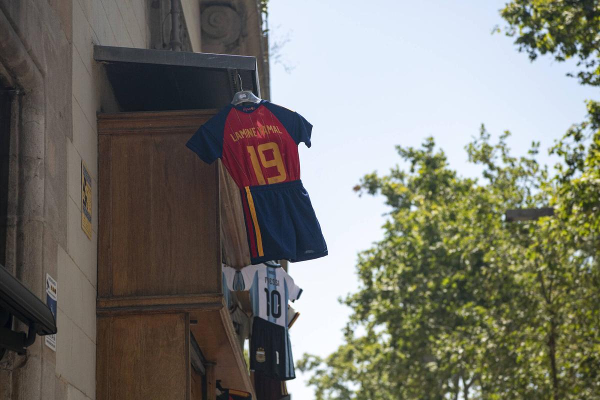 Conjunto deportivo infantil colgando de la fachada de una tienda de souvenirs en la Rambla de Catalunya. Barcelona, 17 de julio de 2026. Foto: Belén González / EP