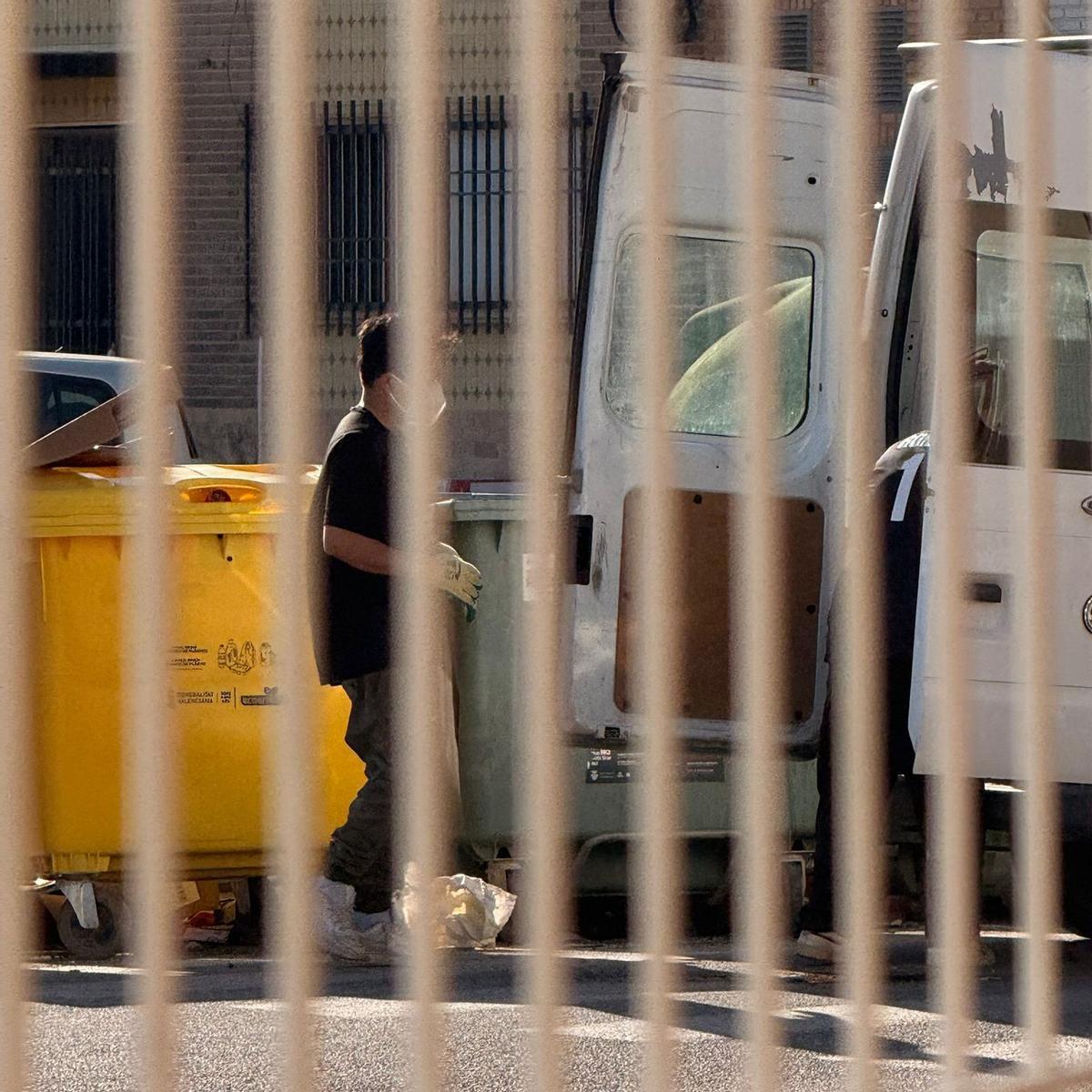 Dos personas vacían una furgoneta en un contenedor en Xirivella.