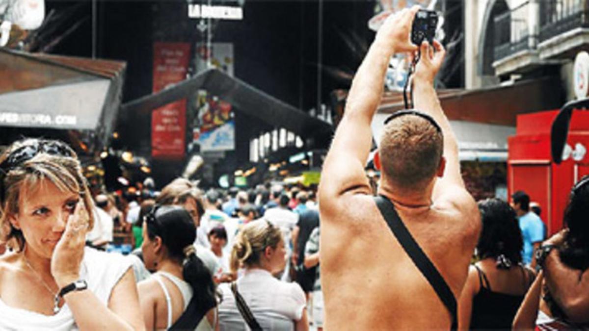 Un turista con el torso desnudo pasea por las calles de Barcelona.