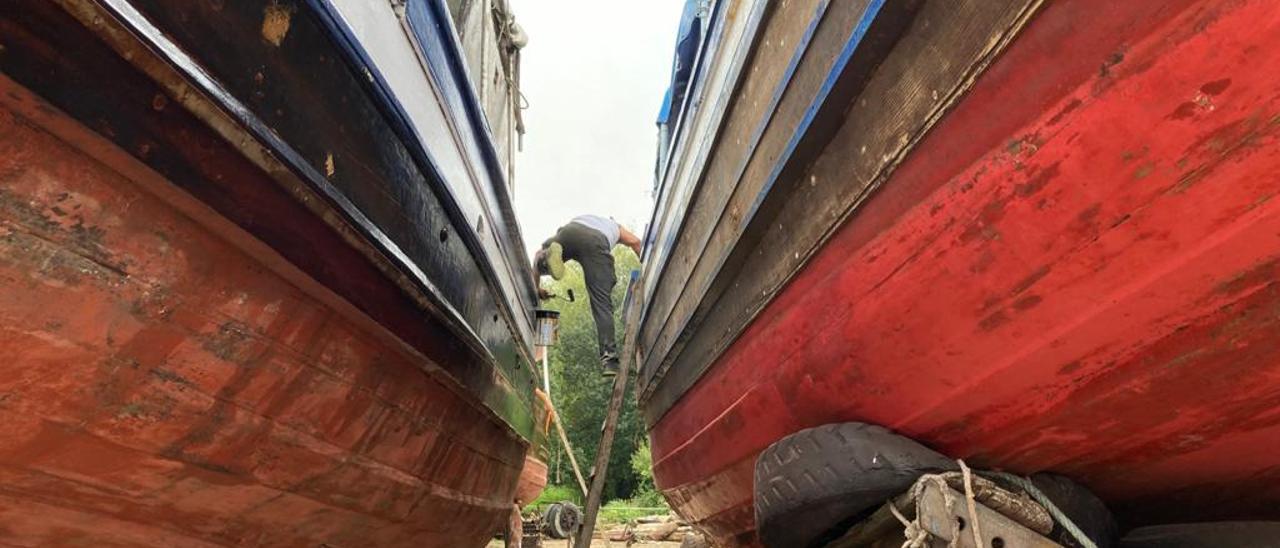 Un hombre pasa de un barco a otro en uno de los astilleros repletos de naves en fase de reparación o pintado, ayer.