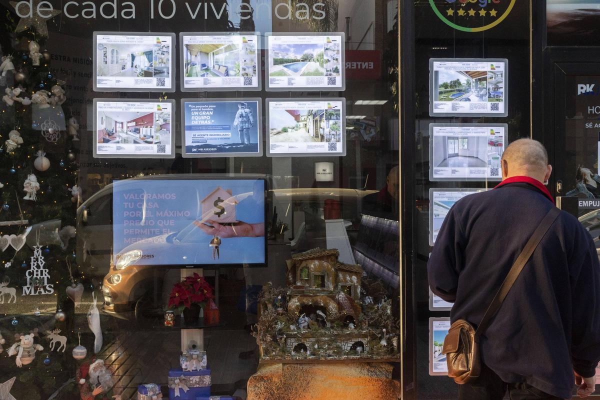 Un hombre observa el escaparate de una inmobiliaria en Torrent.