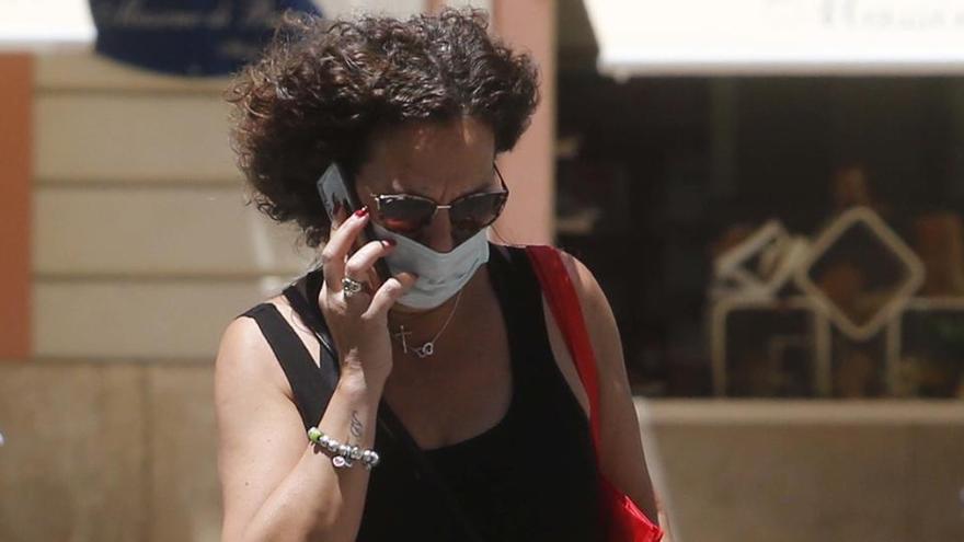 Una mujer con mascarilla habla por teléfono.