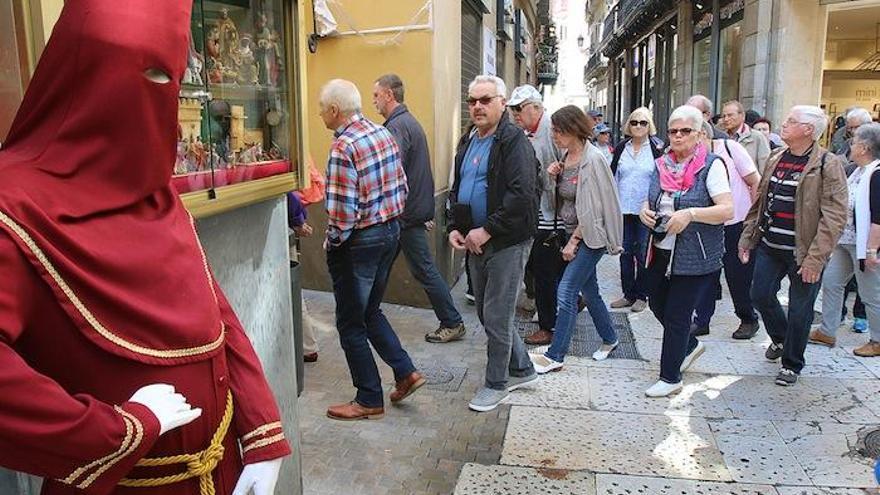 Turistas pasan por delante de la figura de un nazareno en el Centro de Málaga, en una imagen tomada ayer.