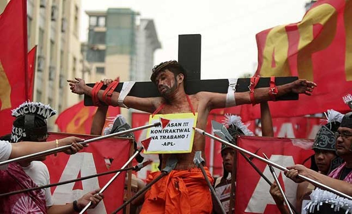 Un filipí representa la crucifixió de Jesús durant una protesta a prop del palau presidencial de Malacanang, a Manila (Filipines) per dramatitzar la situació dels treballadors.