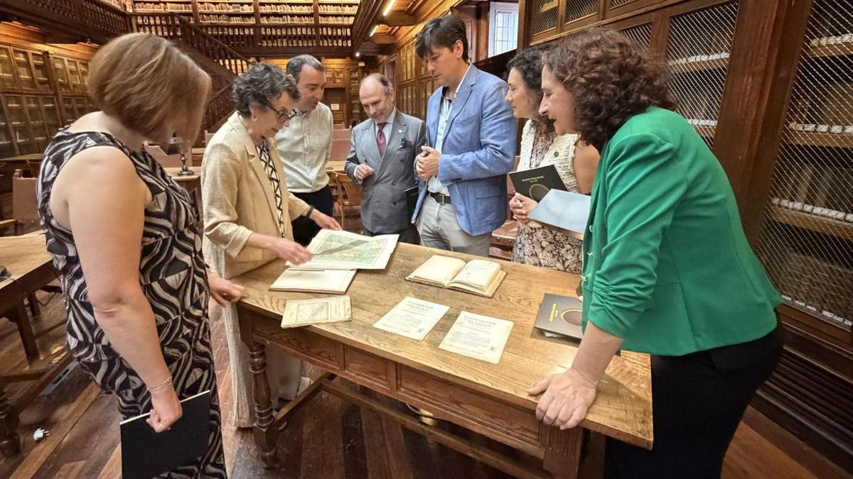 María José Ferrer, segunda por la izquierda, mostrando las publicaciones antiguas sobre el eclipse en la biblioteca de la Unviersidad.