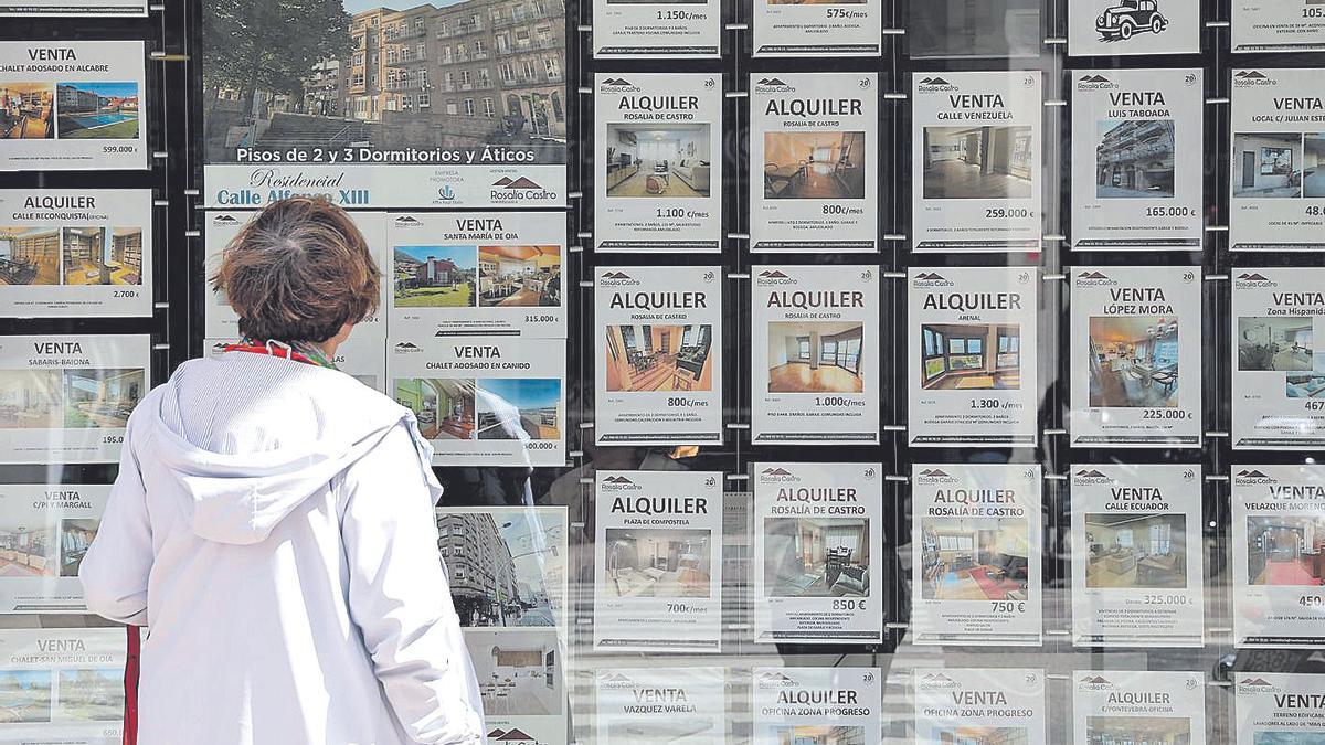 Una mujer ve anuncios de pisos en una inmobiliaria de Vigo