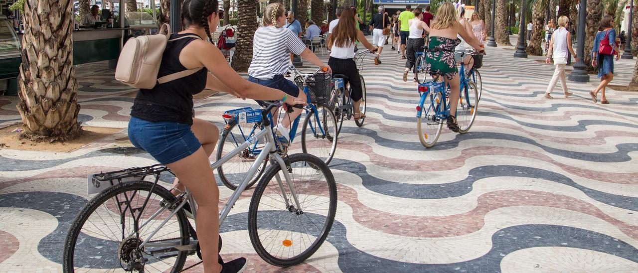 Turistas padelando en bicicleta por el paseo de la Explanada de Alicante