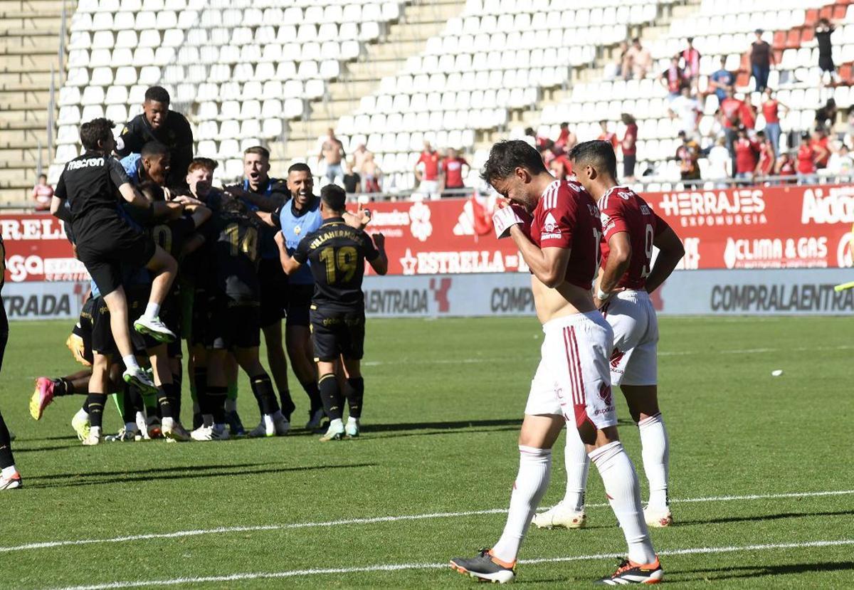 Pedro León se lamenta tras fallar el penalti que daba la victoria al Castellón, cuyos jugadores festejan el triunfo, al fondo, el sábado en la Nueva Condomina.