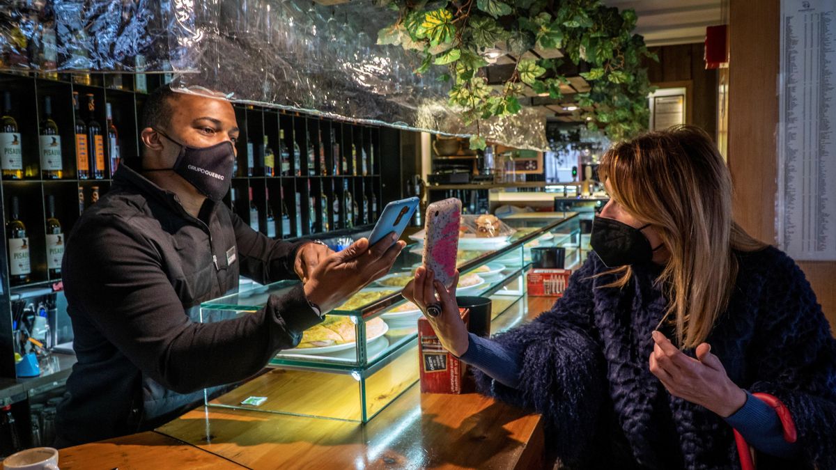 Una clienta usando la mascarilla en un bar.