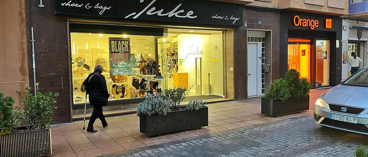 Una mujer frente al escaparate de una zapatería de la calle Benito Pérez Galdós de Alzira, ayer. | R. S.