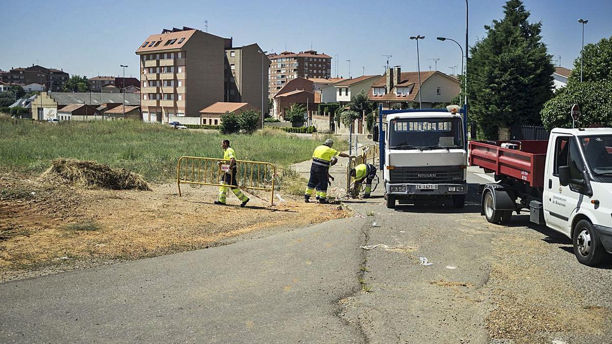 Operarios municipales colocando vallas para delimitar el trazado del vial antes de la expropiación.| J. A. G.