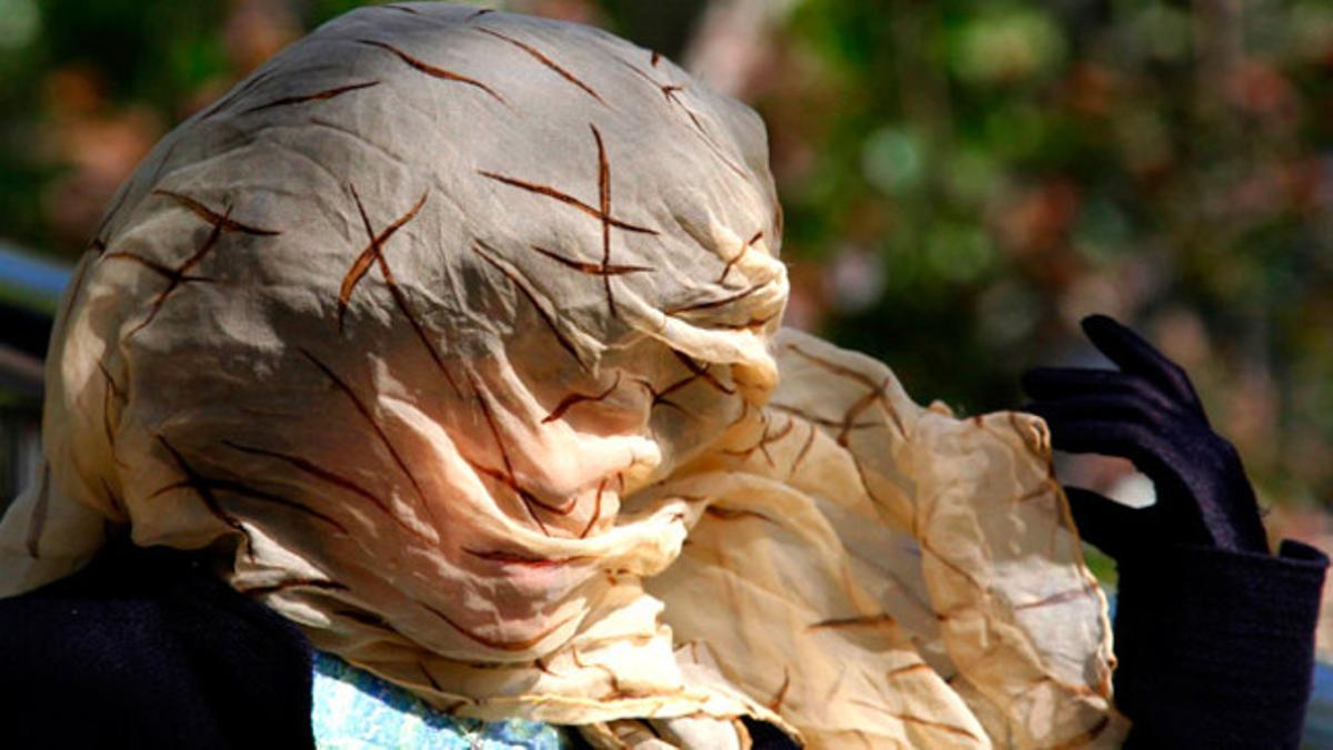 Una dona s¿ajusta el mocador en un dia de vent als carrers de Pequín (Xina).