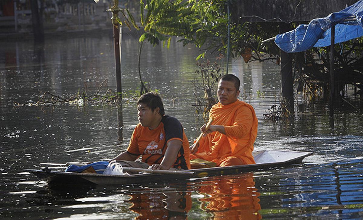 Dos tailandesos s’obren camí entre l’aigua després de les fortes inundacions que han patit a la província de Nonthaburi, als afores de Bangkok (Tailàndia).