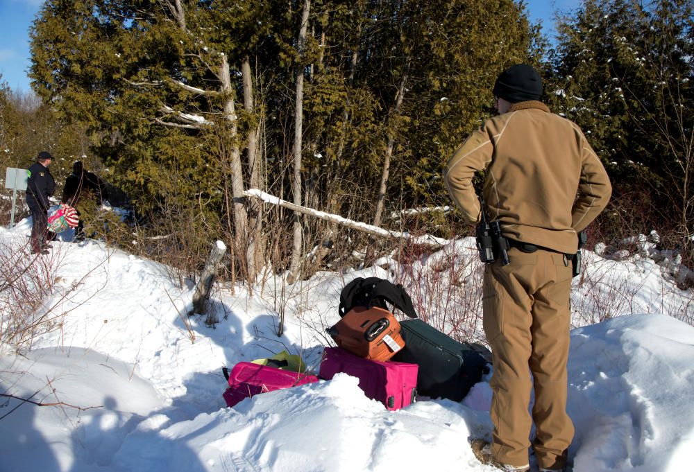 Una patrulla de fronteras estadounidense observa a una familia de Sudán que acaba de cruzar la frontera hacia Canadá (Hemmingford, Canadá).