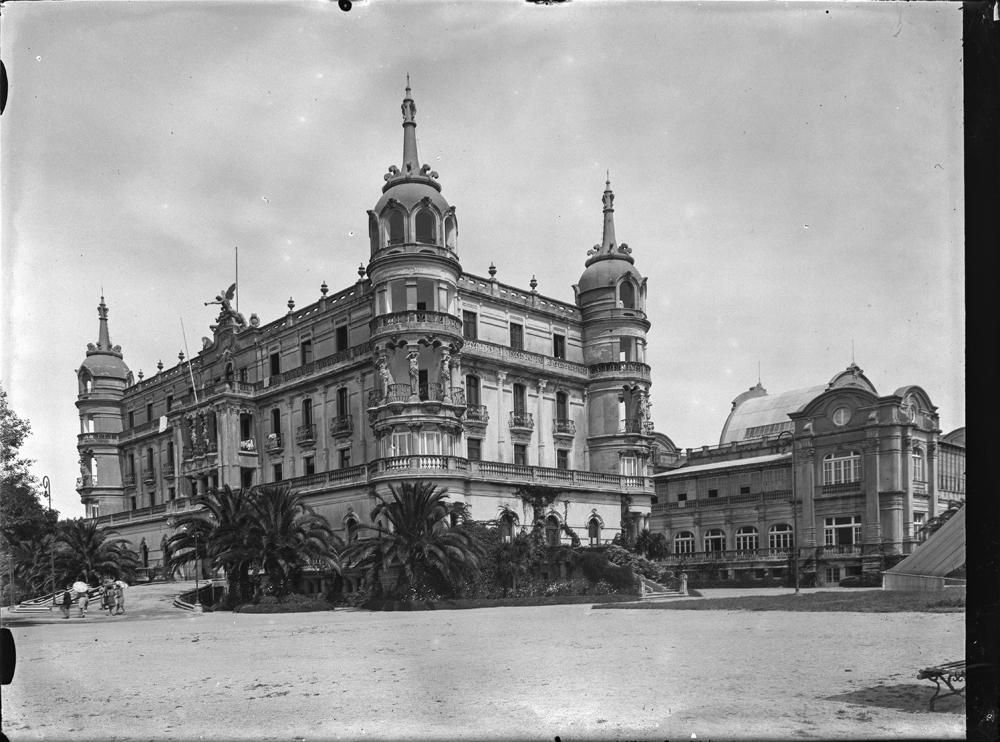 La Toja. Hotel [Hotel de principios del siglo XX con cuatro torres abovedadasHuéspedes con sombrillas en el acceso de entrada. Casino a la derecha 1929-1936.jpg