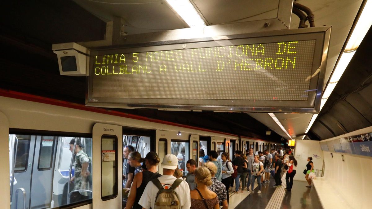 Pasajeros subiendo al metro en la estación de la L5 de metro de Collblanc, con un cartel que muestra una incidencia entre estaciones.