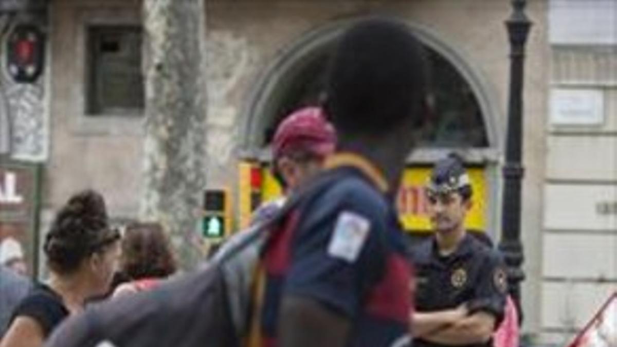 Un policía local observa de cerca a un mantero en la Rambla, ayer.