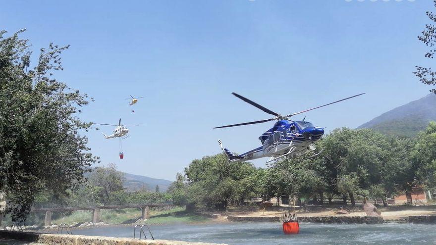 Varios helicópteros toman agua en una piscina natural de la zona de Jerte, este domingo.