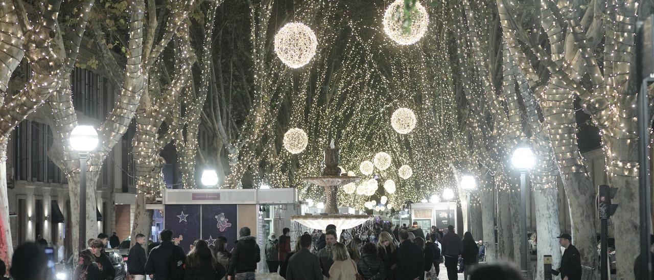 Ciudadanos pasean por la Rambla, que exhiben sus luces de Navidad