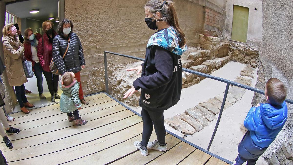 La guia ensenyant una part del carrer medieval que s’ha descobert arran dels treballs arqueològics previs a la restauració del carrer del Balç de Manresa | JORDI BIEL