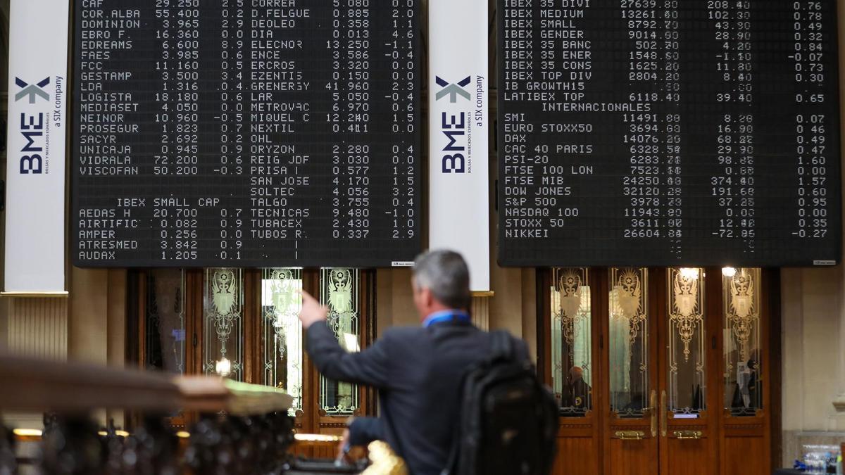 Un hombre señala los paneles de valores del IBEX 35 en el Palacio de la Bolsa de Madrid.