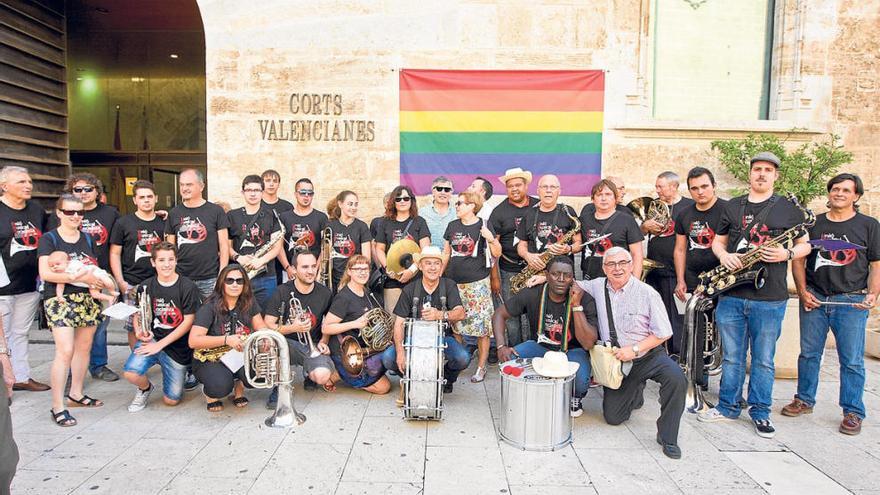 La Unió Musical Socialista, la banda del PSPV, en la puerta del parlamento valenciano con la bandera arcoíris de fondo.