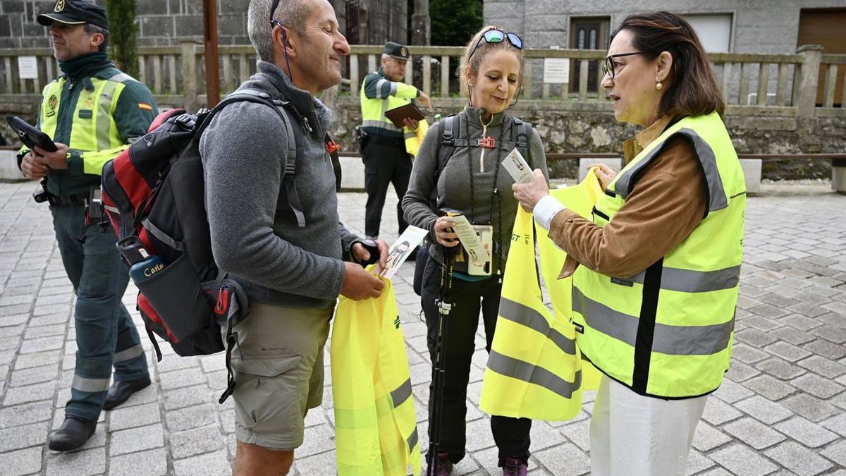 Maica Larriba entrega dos chalecos a dos peregrinos del Camiño de Santiago.  // RAFA VÁZQUEZ