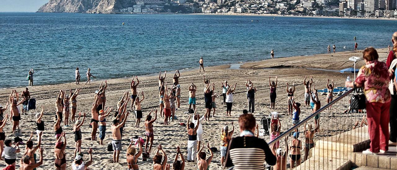 Un grupo de turistas jubilados hace gimnasia en 2019 a primera hora de la mañana en la playa de Levante de Benidorm. | DAVID REVENGA