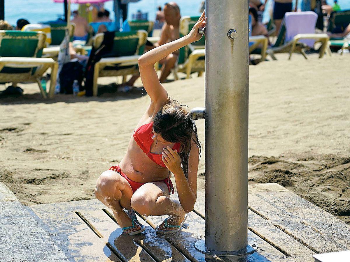 Una joven se enjuaga en los lavapiés de la playa en La Malagueta