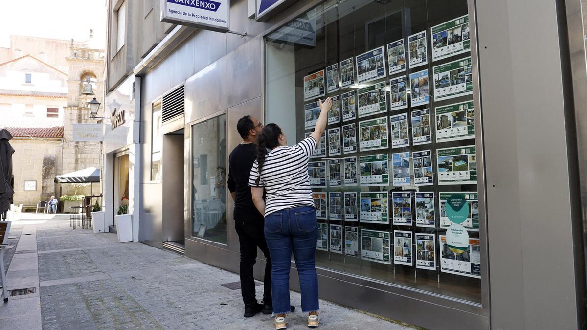 Una pareja observa el escaparate de una inmobiliaria en Sanxenxo