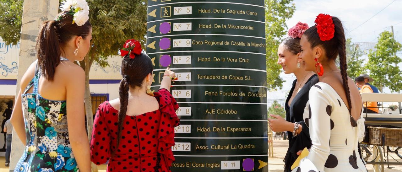 Varias jóvenes señalan las casetas con punto violeta de una calle de la Feria de Córdoba.