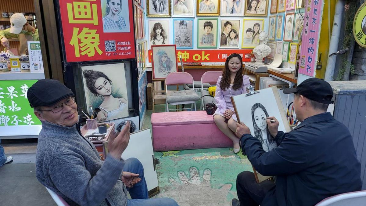 En la imagen, una chica es retratada por un hombre en un hutong de Pekín.