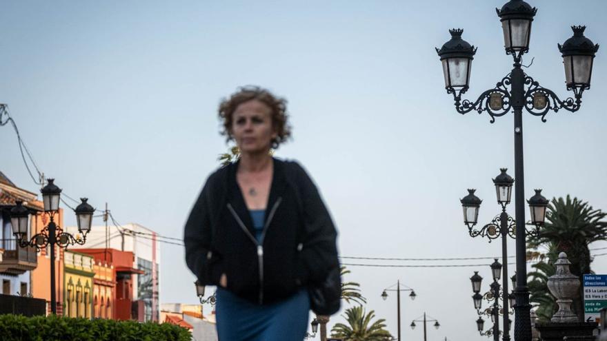 Una mujer camina por un paseo con farolas en La Laguna.