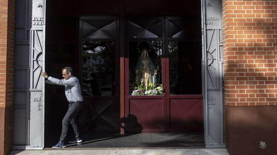 El párroco de San Lorenzo, en el barrio de Los Bloques, abre las puertas de la iglesia para mostrar a la Virgen Milagrosa.