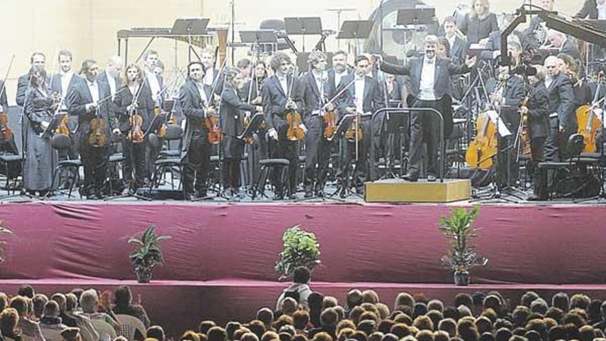 El director de la Sinfónica, Víctor Pablo Pérez, en el centro de la formación, ayer, sobre el escenario de la plaza de María Pita. / juan varela