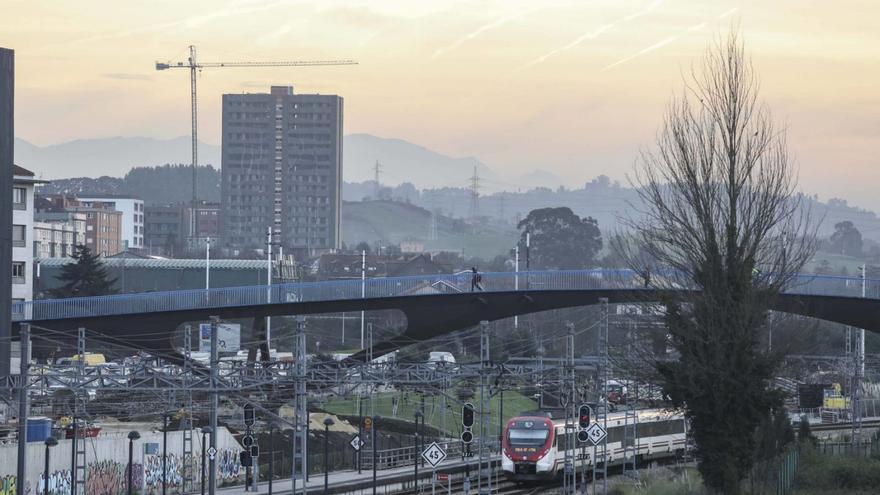 Un tren en tránsito por el casco urbano gijonés pasa por debajo de la pasarela que conecta Moreda y el Polígono.  |  PABLO SOLARES