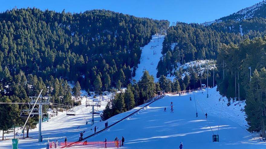 Diversos esquiadors baixant per una de les pistes de Masella (Cerdanya) i altres persones pujades a un teleesquí de l&#039;estació