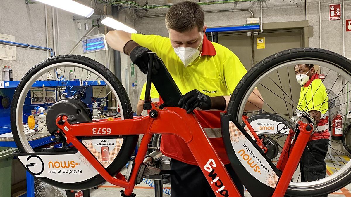 Un operario del Bicing introduce la batería en una bicicleta mecánica que pasará a ser eléctrica