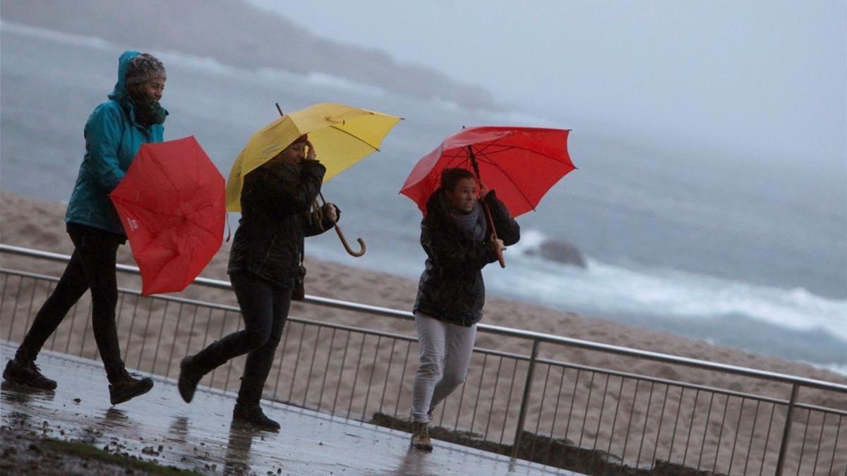 Tres mujeres se protegen del viento y la lluvia en La Coruña al paso de la borrasca Ana, el pasado 12 de diciembre