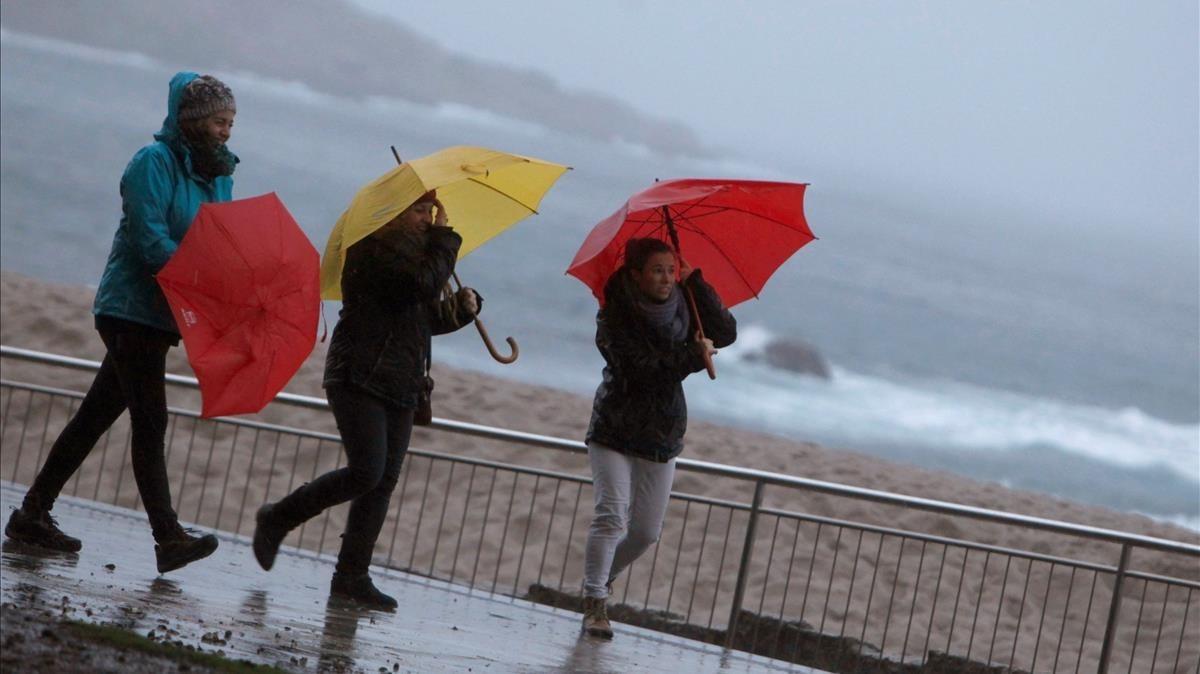 Tres dones es protegeixen del vent i la pluja a la Corunya al pas de la borrasca ’Ana’, el 12 de desembre.