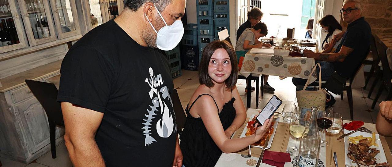 Una clienta muestra el certificado COVID en un restaurante de Vigo, en julio pasado. |   // ALBA VILLAR